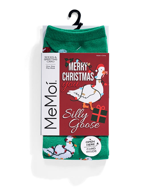 A pair of green Christmas-themed socks in retail packaging with a hanger, featuring a red card that reads 'Merry Christmas you Silly Goose' with an illustration of a goose.